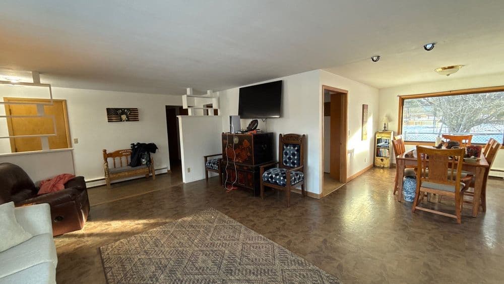 Open living area with a couch, dining table, and large windows for natural light.