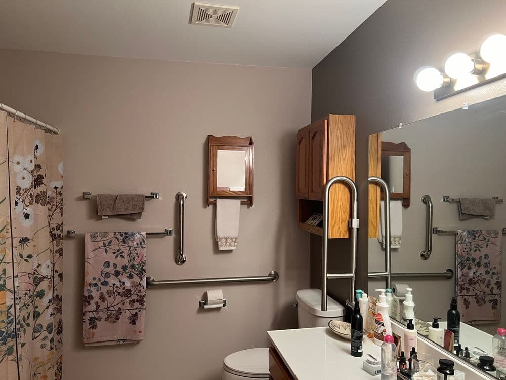 Modern bathroom with floral shower curtain, mirror, and organized toiletries on the counter.