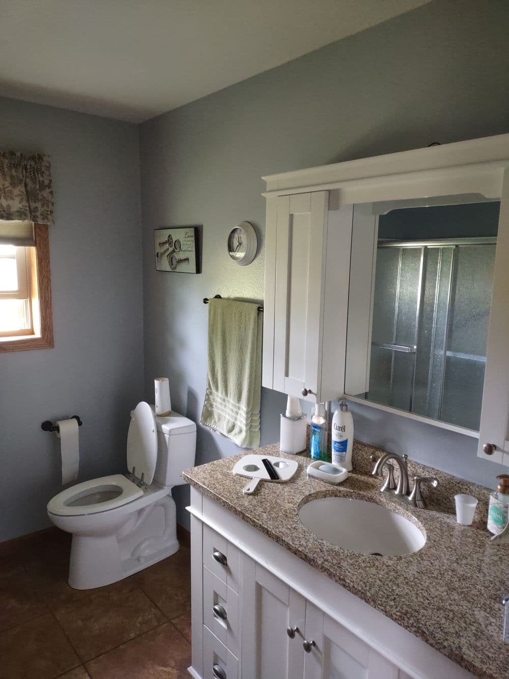 Modern bathroom with white cabinetry, granite countertop, and shower enclosure. Clean and spacious.