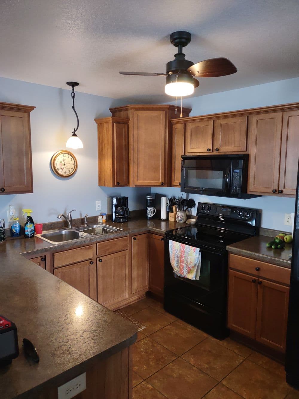 Modern kitchen with wood cabinetry, stainless appliances, and ceiling fan, featuring a cozy layout.