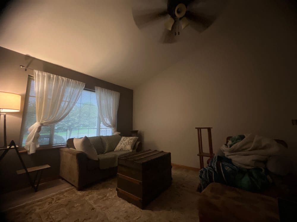 Cozy living room with a sofa, wooden coffee table, and large window with sheer curtains.