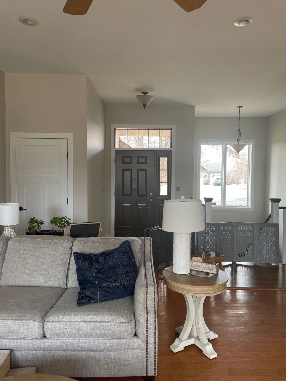 Cozy living room featuring a sofa, lamp, and front door with natural light.
