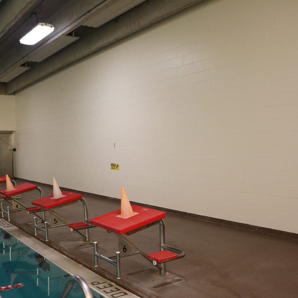 Empty swimming pool area with red benches and orange cones along the wall.
