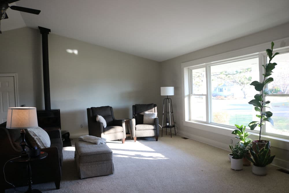 Modern living room with two armchairs, a floor lamp, and a large window. Bright and inviting space.