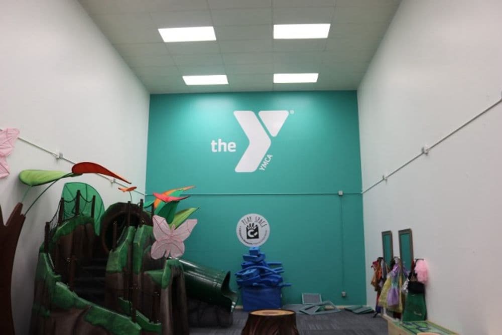 YMCA play area with colorful structures and vibrant decorations on teal wall.